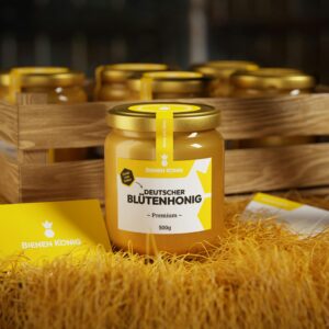 Jar of premium German flower honey on straw with other jars in a wooden crate.