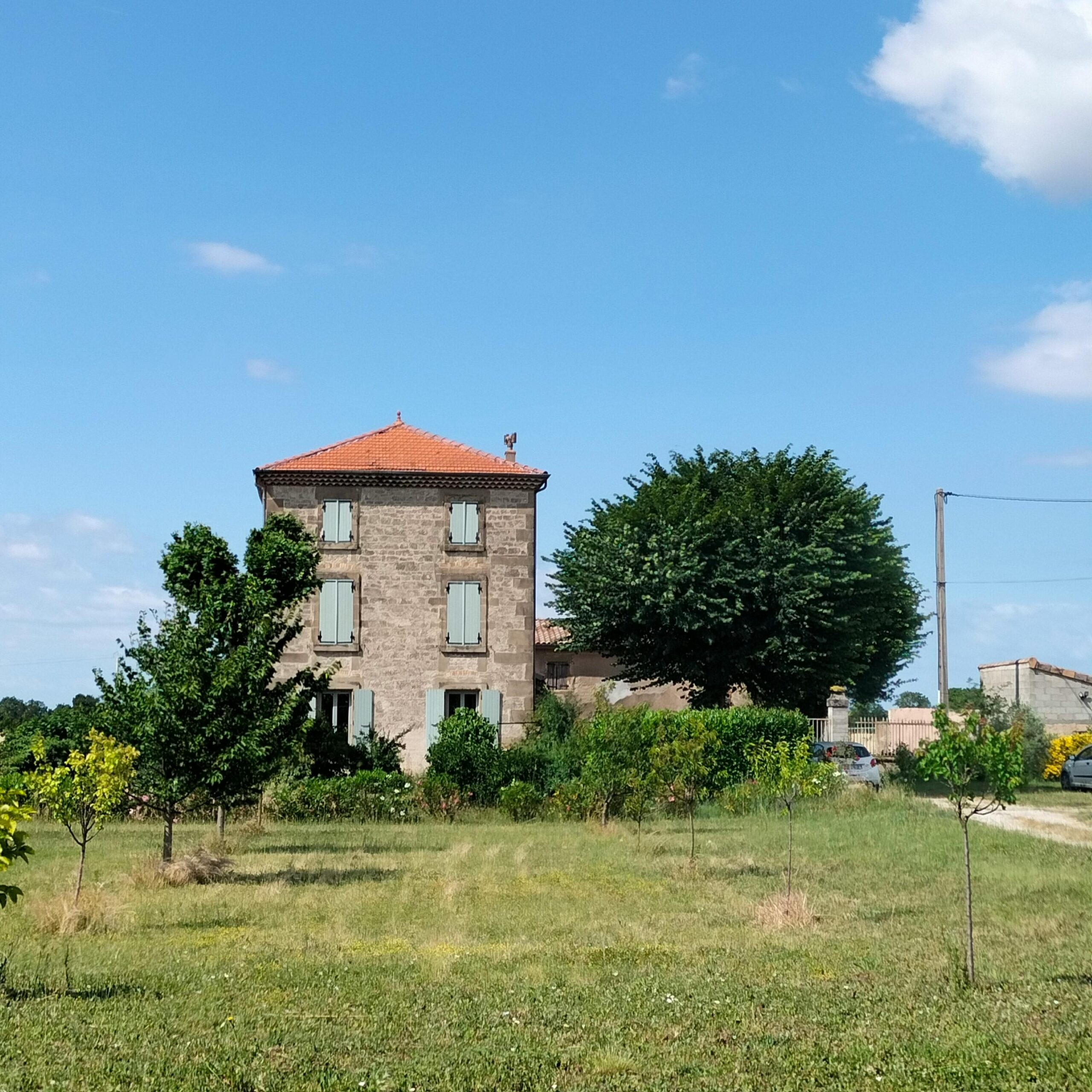 Beautiful countryside house surrounded by greenery under a clear blue sky.